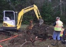 A construction worker uses construction equipment to dig a hole for fiber.