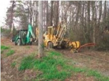 A plowing and trenching crew installs fiber in a wooded area.