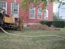 A construction worker drills a hole outside a building.