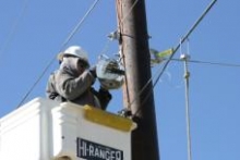 An NTUA crew member begins stringing cable on network poles in New Mexico.