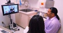 A patient in a doctor’s office speaks with a nurse using video conferencing.